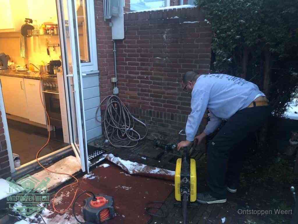 Een monteur werkt buiten bij een open riool-/grondput met een elektrische ontstoppingsmachine om een verborgen afvoerprobleem op te sporen in Weert