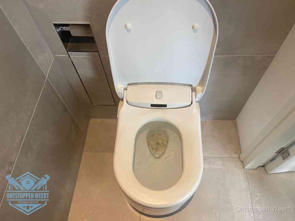 Een wit hangtoilet waarin een prop wc-papier op het water blijft drijven, een duidelijk signaal van een verstopte wc in Weert