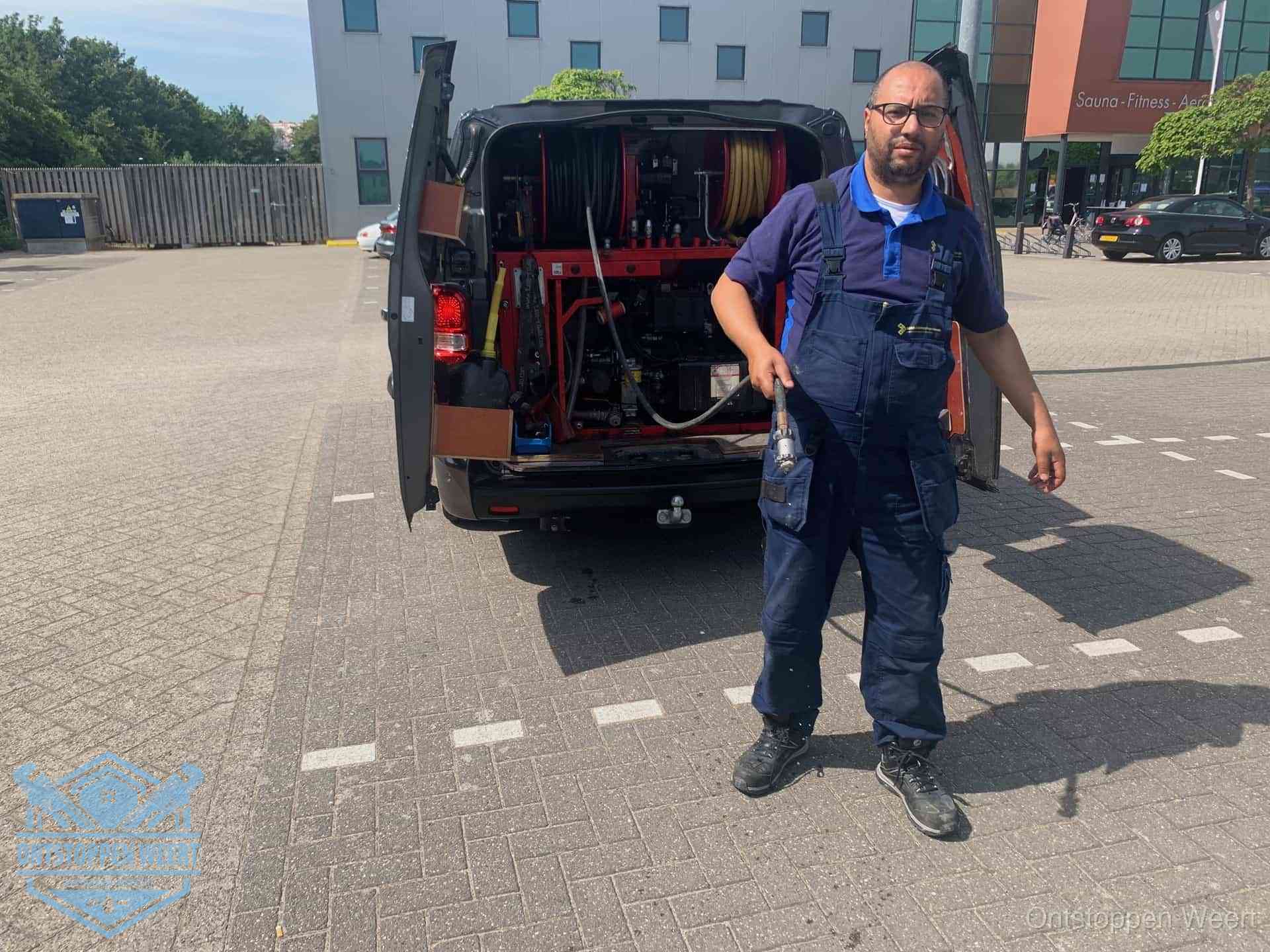 Een monteur bij zijn bestelbus met een hogedruk- en rioolreinigingsunit, klaar om de oorzaak van terugkerende wc-verstoppingen aan te pakken in Weert