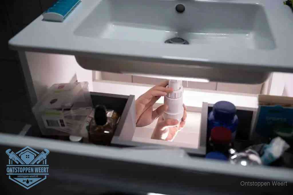 Een pompfles met zeep boven een wastafel in de toiletruimte, de warm water en afwasmiddel-methode om de wc te ontstoppen in Weert