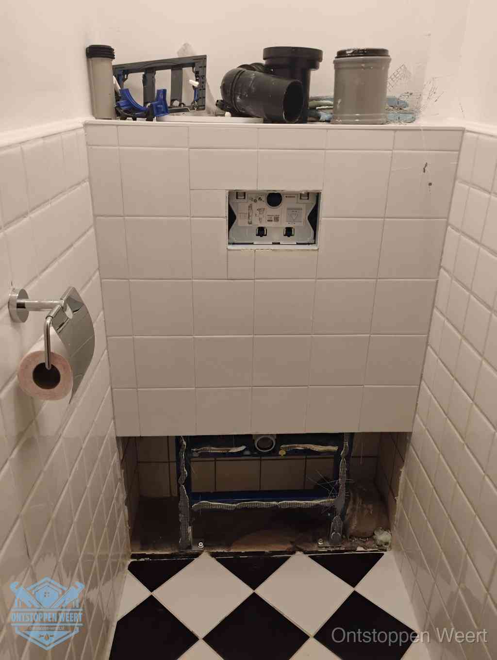 Een toiletruimte waar het hangtoilet en de inbouwreservoir-onderdelen zijn vrijgelegd voor onderhoud, periodiek nazicht voorkomt een wc-verstopping in Weert